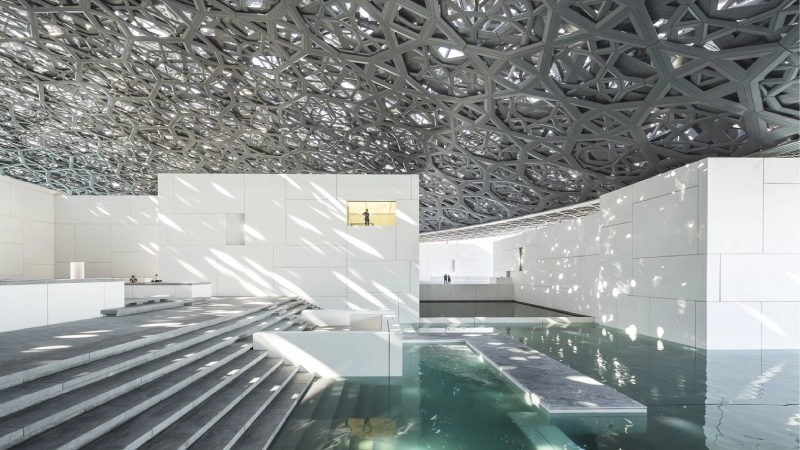 Louvre Abu Dhabi dome with sunlight rays creating geometric patterns at midday UAE