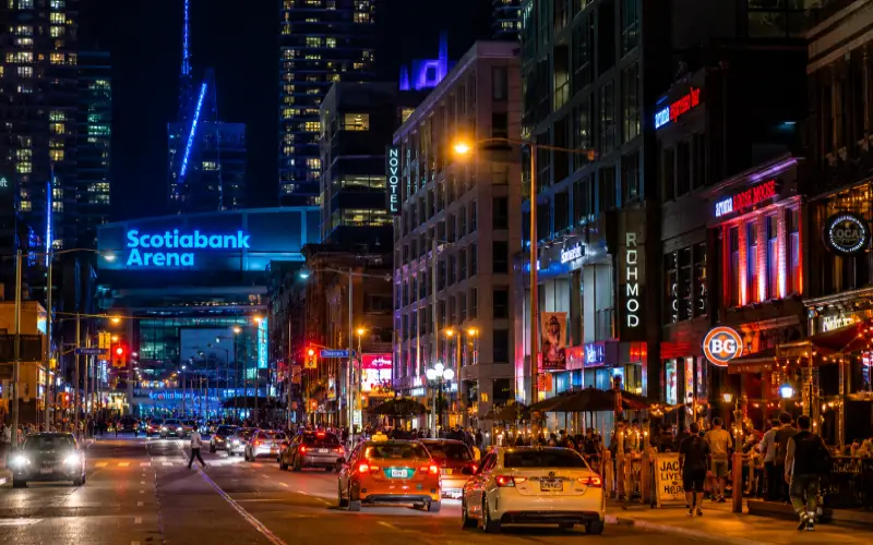 Toronto Entertainment District at night showing Scotiabank Arena lights and King Street hotel buildings for visitor accommodation guide