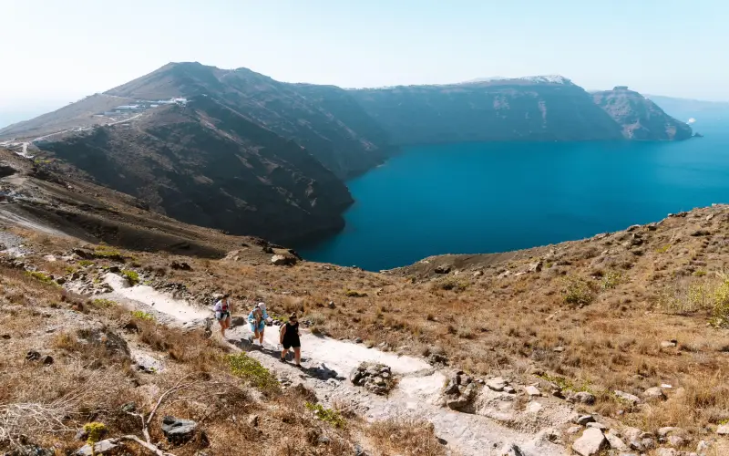 Hikers walking along the Fira to Oia caldera trail with panoramic views of the Aegean Sea and Santorini cliffs