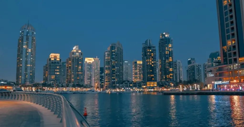 The Dubai Marina skyline lit up in the evening with skyscrapers reflecting on the water.