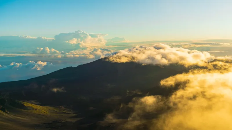 Couple watching the sunrise above the clouds at Haleakala National Park in Maui Couple watching the sunrise above the clouds at Haleakala National Park in Maui 