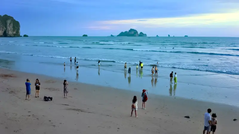 Family enjoying calm shallow water at Ao Nang beach in Krabi 