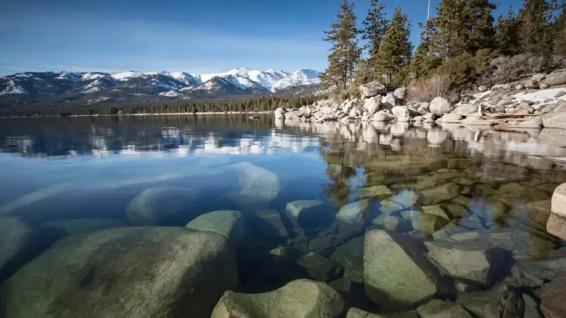 Crystal clear water of Lake Tahoe surrounded by Sierra Nevada mountains 