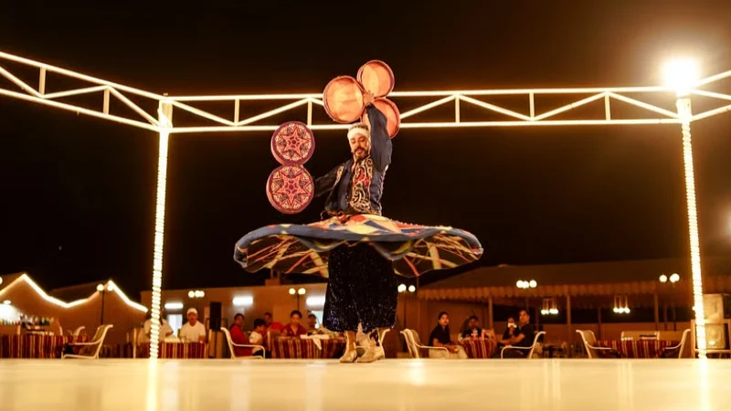 Tanoura dance performer spinning during a fire show at a Dubai desert camp