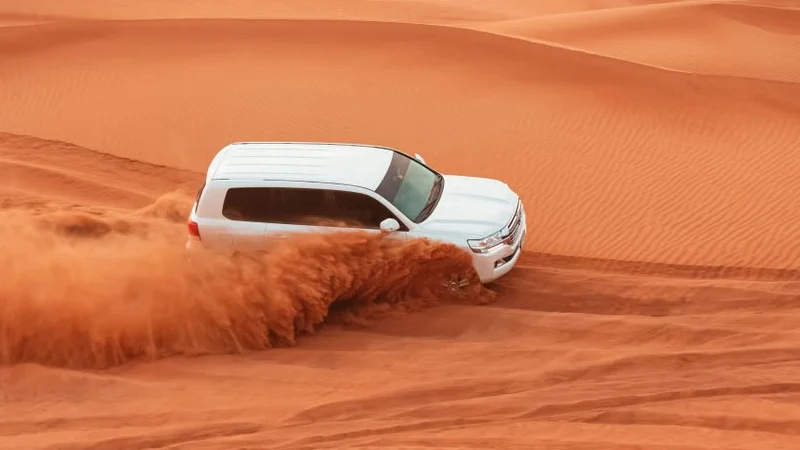 4x4 vehicle performing dune bashing on red sand dunes in Dubai 4x4 vehicle performing dune bashing on red sand dunes in Dubai