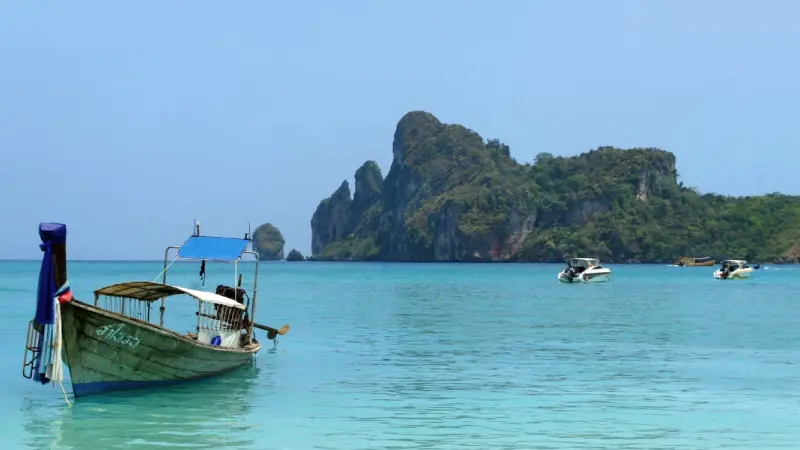 Longtail boat on a tropical beach in Thailand with clear turquoise water