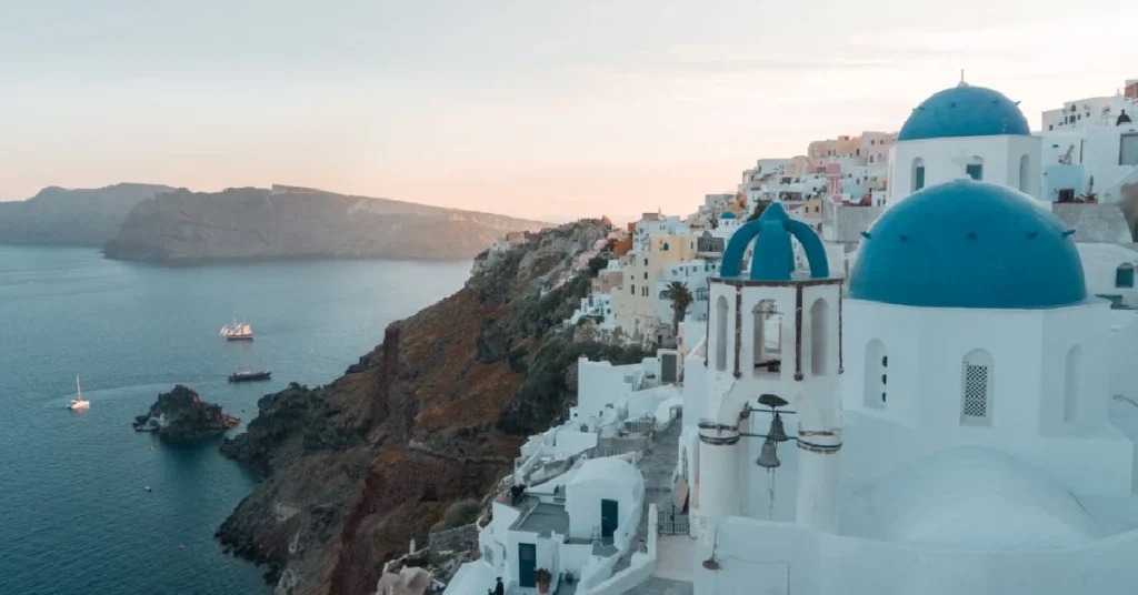 Nicest Places In Europe To Visit Blue-domed churches and whitewashed buildings in Oia, Santorini at sunset