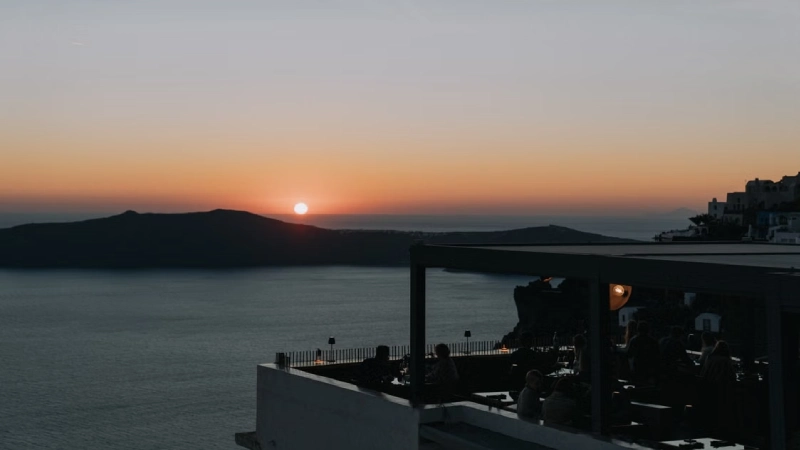 A candlelit dinner table overlooking the Santorini caldera at dusk