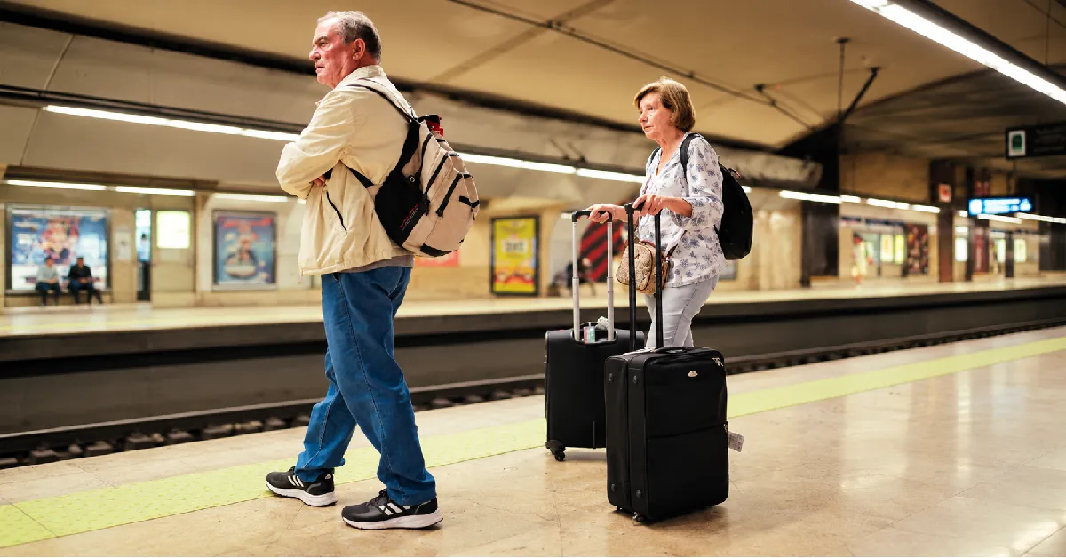 Senior couple walking through an airport with luggage, ready for a tri