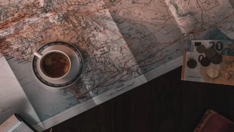 Travel planning notebook and map laid out with coffee