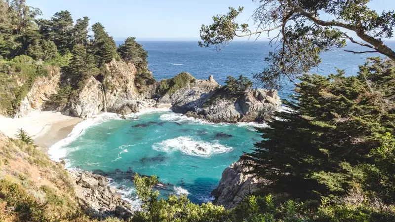 McWay Falls dropping onto a small beach in Big Sur, seen from the roadside viewpoint